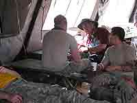 Photo of three men in camouflage in military medical tent.
